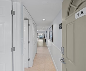 Stylish corridor with framed artwork and modern door handles leads to a room with an outside view.