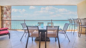 Un balcon avec vue sur la mer, aménagé avec une table et des chaises, et un mur en pierre sur un des côtés.