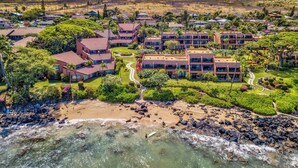 A resort with multiple buildings, a beach, and a rocky shoreline.
