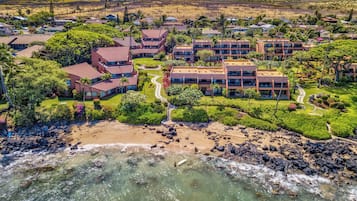 Ein Resort mit mehreren Gebäuden, einem Strand und einer felsigen Küstenlinie.