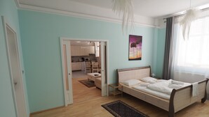 A bedroom with a wooden bed, a small bedside table, a nightstand, a chair, and a large window with curtains. - New apartment in the city center (Praha)