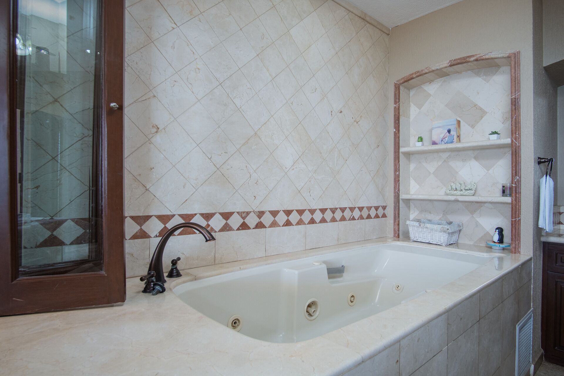 Ein Badezimmer mit einer großzügigen Badewanne, einer Duschkabine aus Glas und einer Fliesenwand mit Rautenmuster.
