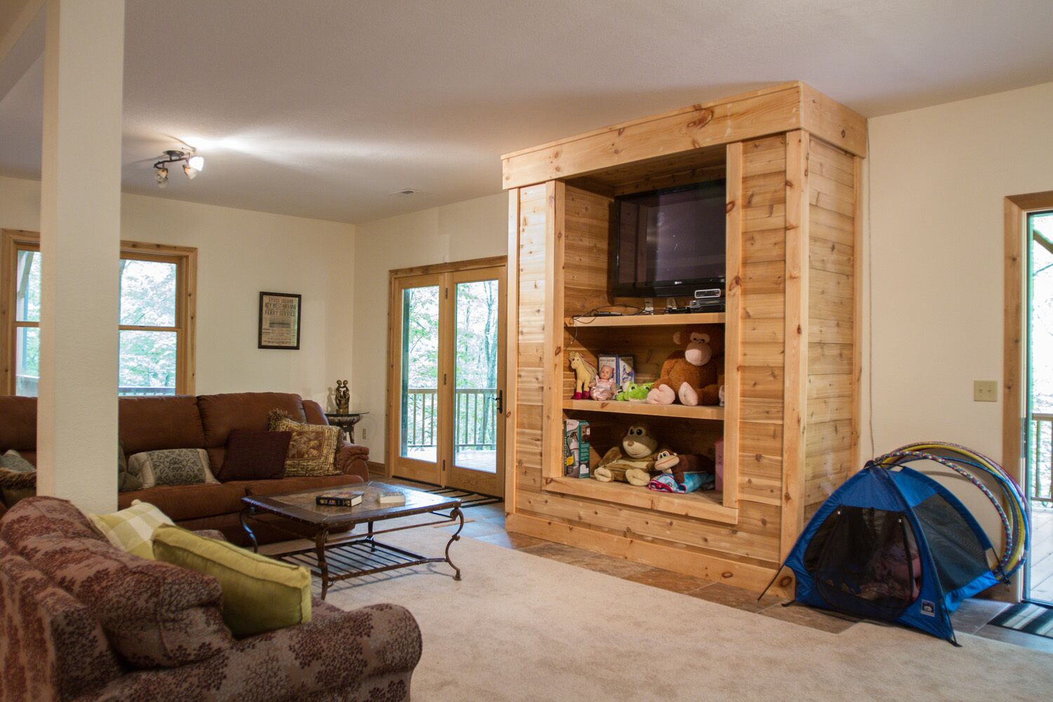 Een gezellige woonkamer met een houten tv-meubel, een bank, een salontafel en een tent.