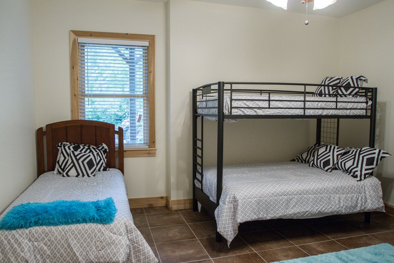 Un dormitorio con dos camas, una con cabecera de madera y la otra, estilo litera de metal.