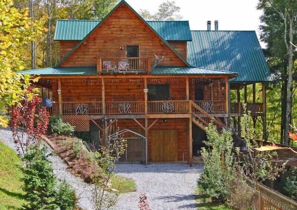 A wooden cabin with a green roof, a balcony, and a covered porch. - 7 Bedroom 5.5 Bath Stunning Luxury Log, Reunions & Weddings Welcomed (Maggie Valley)