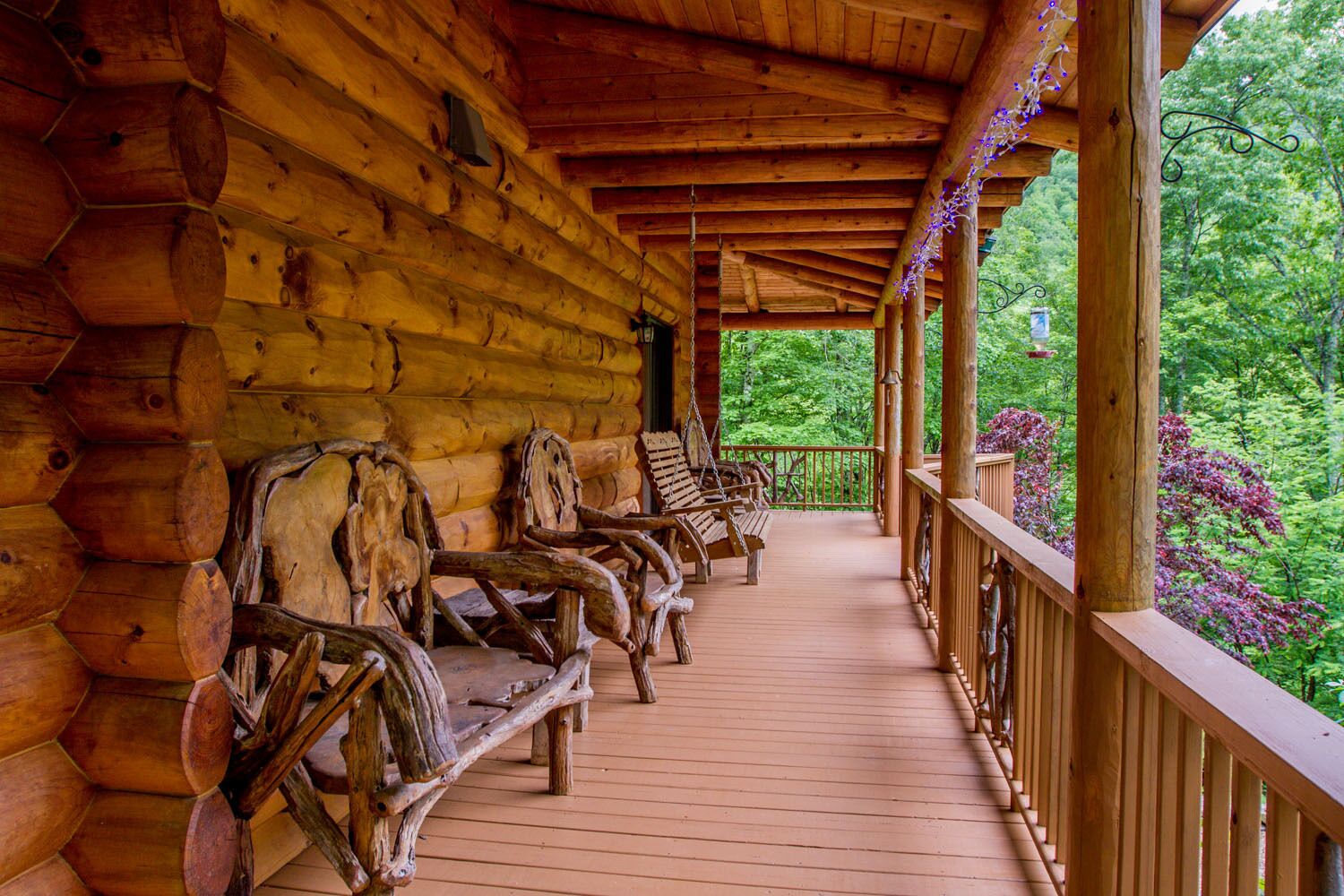 A wooden log cabin with a porch featuring rustic wooden benches and a railing.