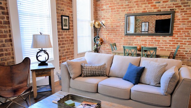 A living room with a brick wall, a sofa, a coffee table, a lamp, and a chair.