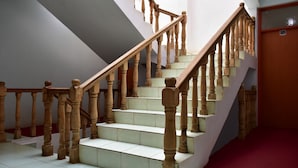 Una escalera con balaustres de madera y escalones blancos que conduce a una plataforma con alfombra roja.