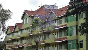 Un hotel de varios pisos con fachada verde y techos de tejas rojas.