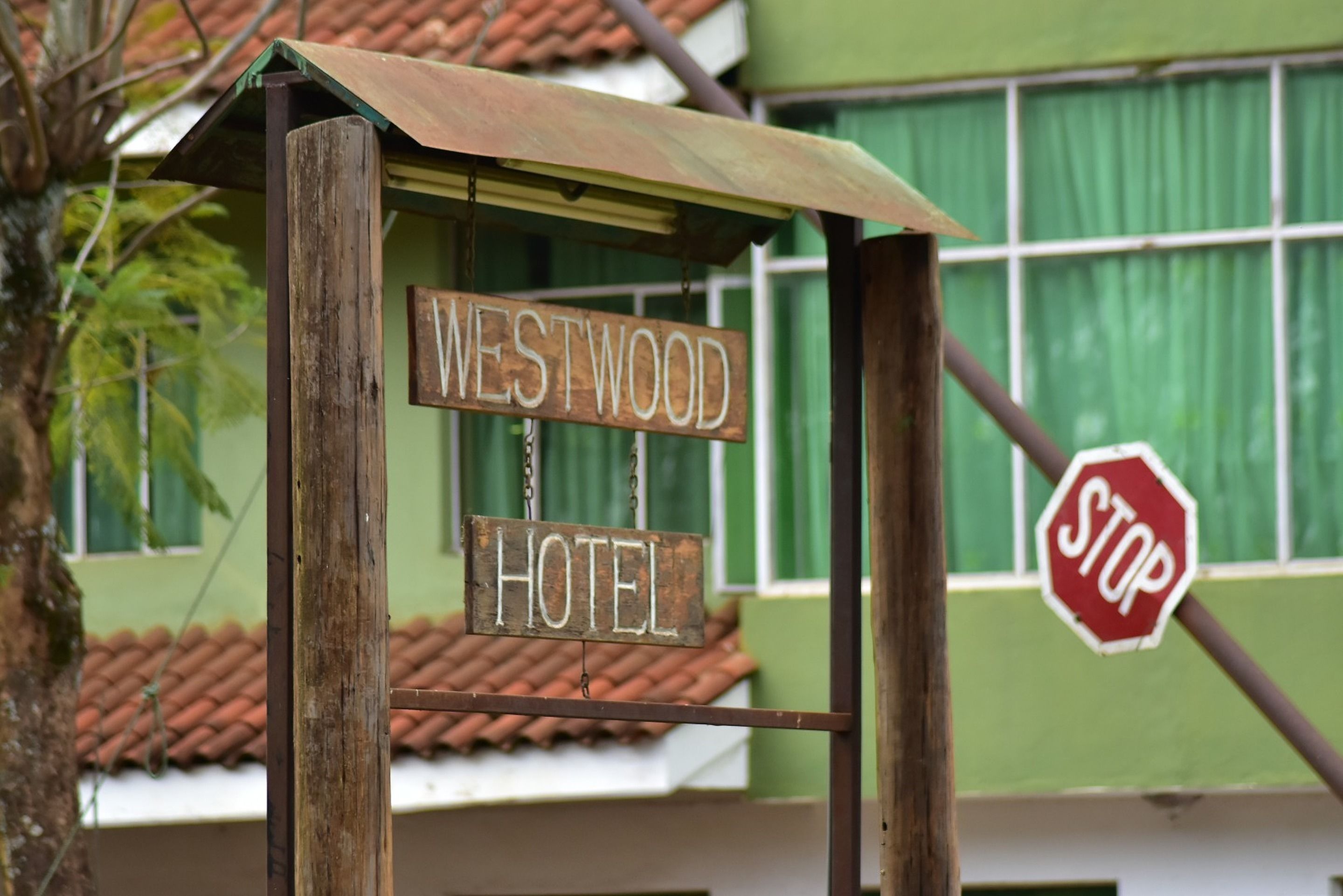 Un letrero de madera con la leyenda "WESTWOOD HOTEL" colgado de una estructura metálica.