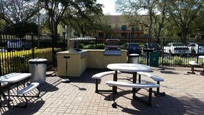 Eine Außenpatio mit Grillanlagen, Picknicktischen und Mülleimern.