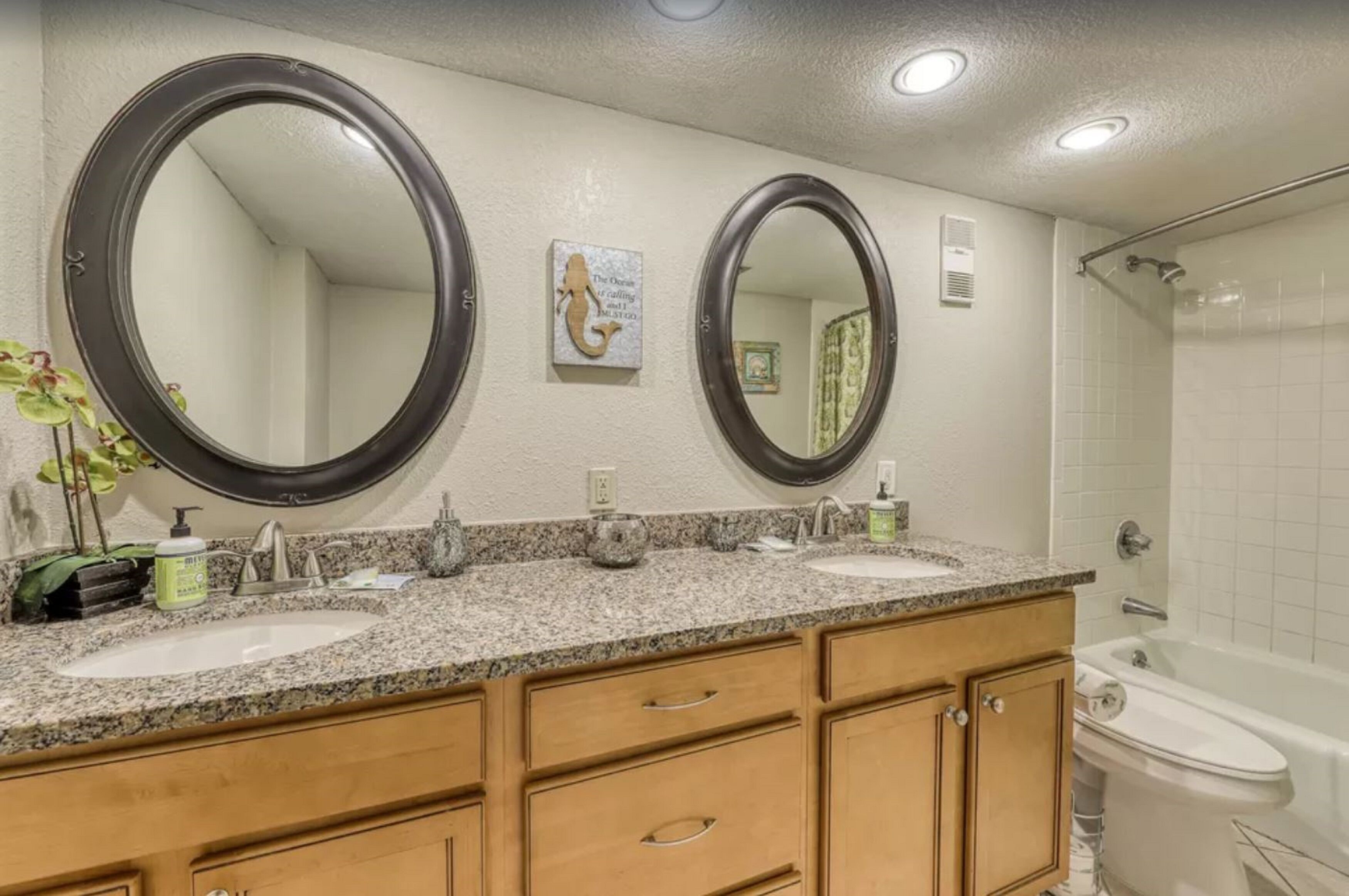 A bathroom with two sinks, a large mirror, and a bathtub.