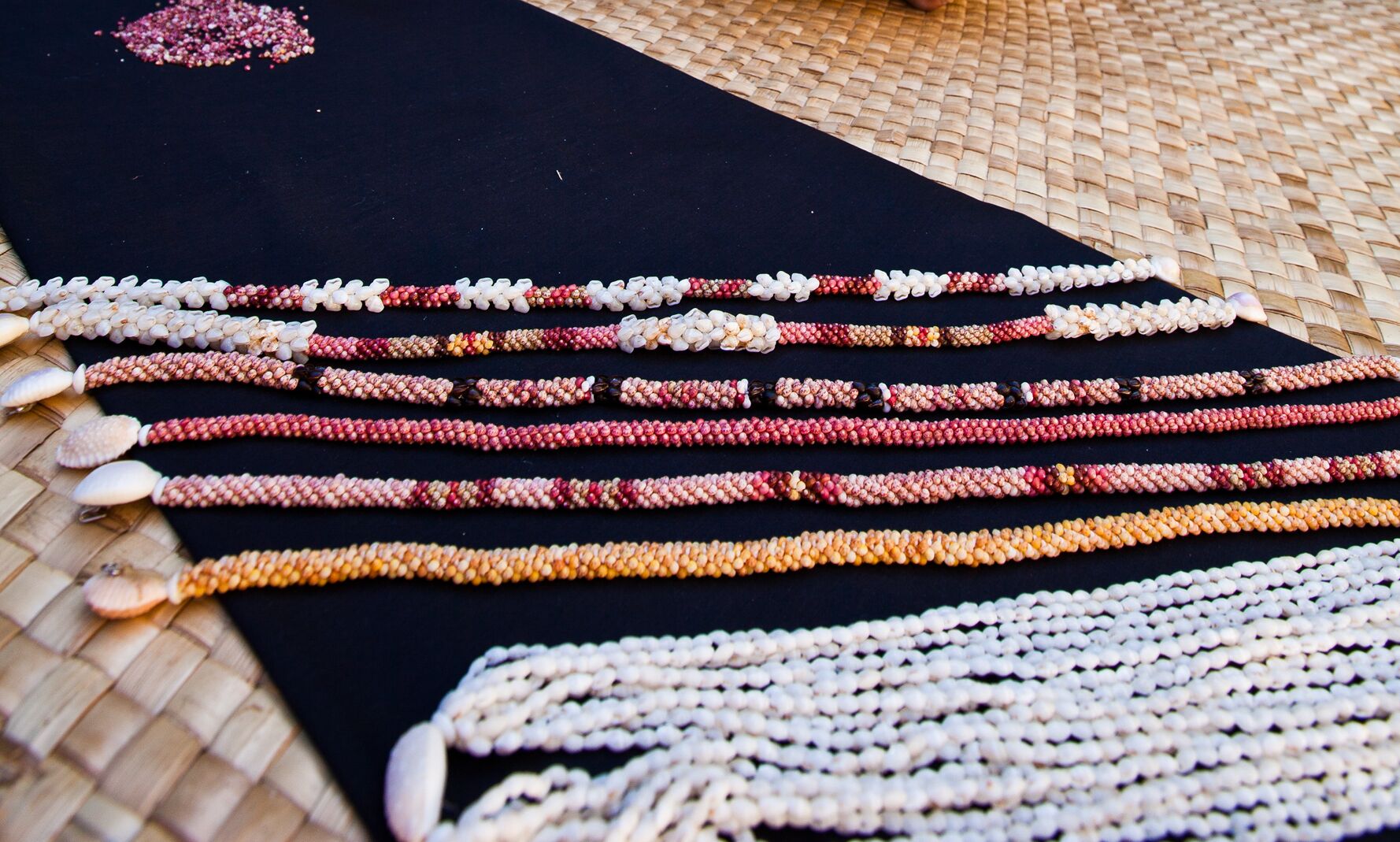 Une collection de colliers ornés de perles, disposés sur une surface noire.