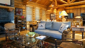 A log cabin interior with a sofa, chairs, a glass coffee table, and a fireplace. - JHRL - Beautiful Single-Family Granite Ridge Cabin #7590, Hot Tub (Teton Village)