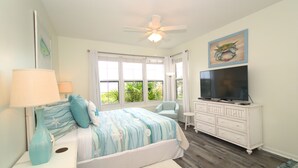 A bedroom with a bed, a TV, a ceiling fan, a dresser, and a window with a view of greenery. - 105W ~ 2BR/2BA condo with Beachfront View (Gulf Shores)