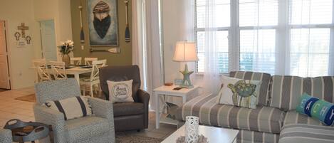 A living room with a sofa, armchairs, a coffee table, and a dining area with chairs and a table.