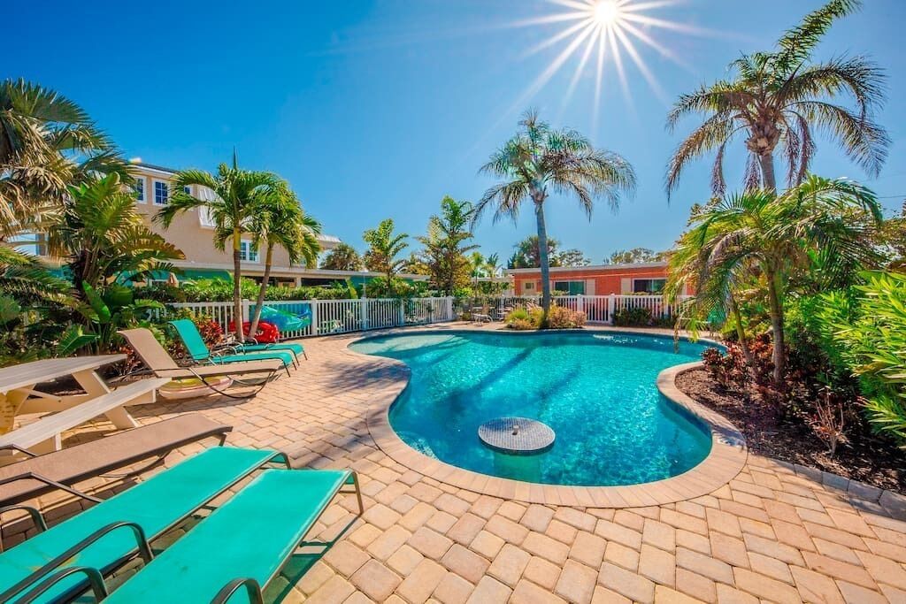 A pool area with lounge chairs and palm trees.