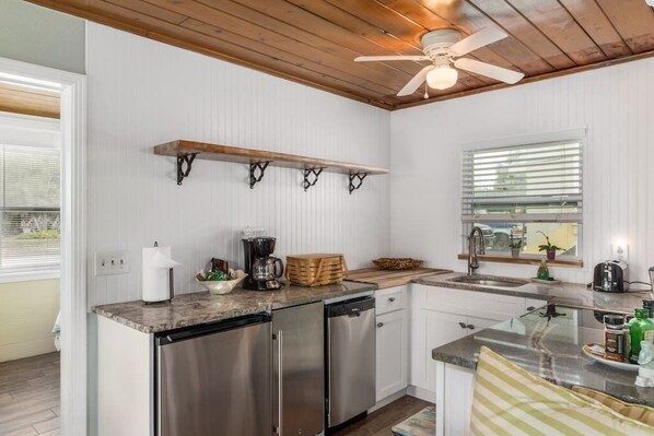 A modern kitchen with white walls, wooden ceiling, and built-in appliances.