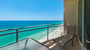 A balcony with a clear view of the ocean and a pier, featuring a glass table and two chairs. - 2305 - Gulf Front Living with Breathtaking Views (Panama City Beach)