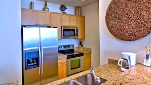 A modern kitchen with stainless steel appliances, granite countertops, and wooden cabinets. - 2305 - Gulf Front Living with Breathtaking Views (Panama City Beach)