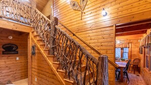 Ein rustikales Interieur mit einer Holztreppe, einem Essbereich und einem Kamin.