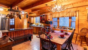 Ein Holzblockhaus-Interieur mit Küche, Essbereich und großen Fenstern.