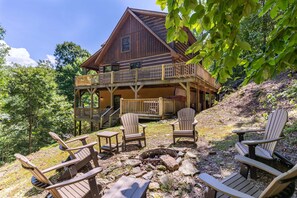 A cabin with a deck, outdoor seating, and a fire pit.