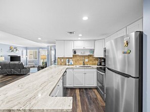 Enjoy cooking in this kitchen with a stainless steel refrigerator, island, oven, and wooden floor.