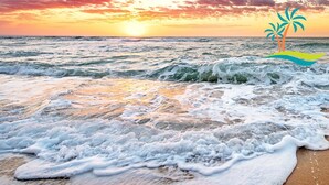 Een strandscène met golven en een zonsondergang.