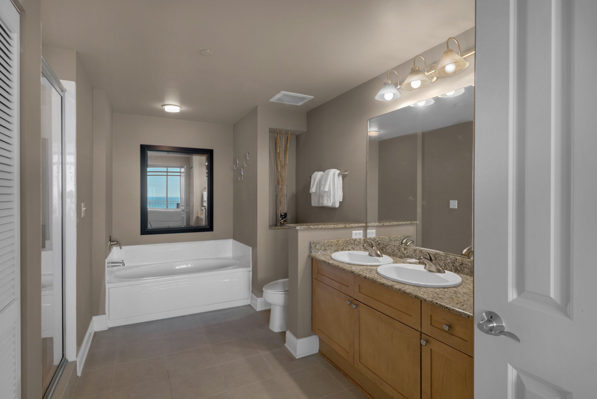 A modern bathroom with a bathtub, two sinks, a large mirror, and a vanity with a countertop.