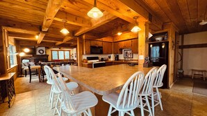 A spacious kitchen with a large island, wooden cabinets, and white bar stools. - Trailside Home on Alpen Trail with Hot Tub & Allows Dogs (Bessemer)