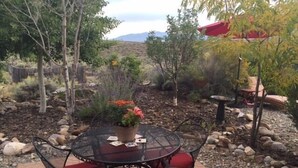 A patio with a round table and chairs, surrounded by rocks and plants.