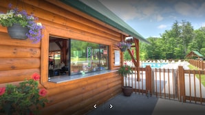 A wooden cabin with a pool area, a bar, and a wooden deck.