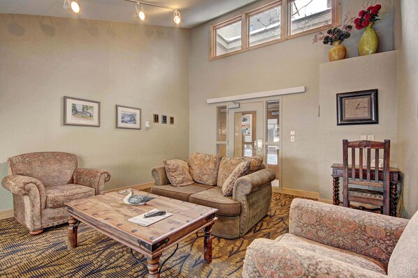 A living room with a patterned rug, a wooden coffee table, a sofa, and a chair. There are framed pictures on the wall and a window above the sofa. - Large Luxury Condo/Located on Keystone Lake/Private Patio with Grill (keystone)