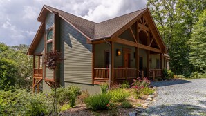 A cabin with a porch, surrounded by a garden and a gravel path.
