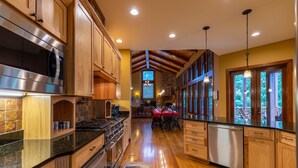 A spacious kitchen with wooden cabinets, stainless steel appliances, and a dining area with a red tablecloth.