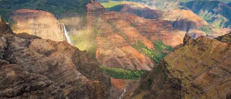 A canyon landscape with layered rock formations and a waterfall.