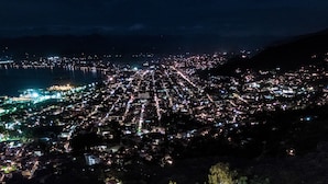 Vista aérea de uma cidade à noite, com ruas e edifícios iluminados.