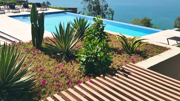 Uma piscina com vista para o mar e montanhas.