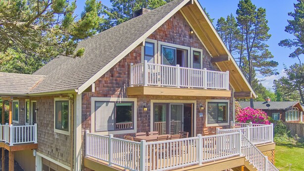 A two-story log cabin with a balcony, a garage, and a small deck with outdoor furniture. - Pets OK, OCEAN VIEW, Beach Path, HOT TUB, Large Yard (FirstM) (Ocean Park)