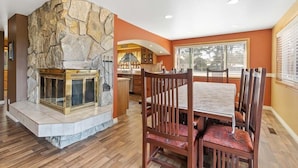 A dining area with a stone fireplace, wooden chairs, and a table. - Pets OK, OCEAN VIEW, Beach Path, HOT TUB, Large Yard (FirstM) (Ocean Park)