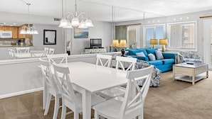 A modern living room with a white dining table, blue sofa, and a TV. - 308- "Embrace Coastal Charm: Experience Beach Cottage Vibes in Destin" (Destin)
