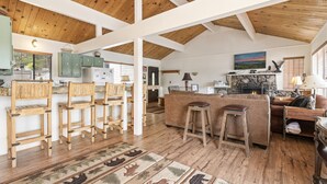 A spacious living area with wooden flooring, a stone fireplace, and a large window with blinds. - LAKEFRONT - Boat Dock! Close to Slopes, HOT TUB! Game room! (Big Bear Lake)