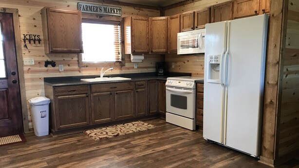 A kitchen with wooden cabinets, a sink, a stove, and a refrigerator.