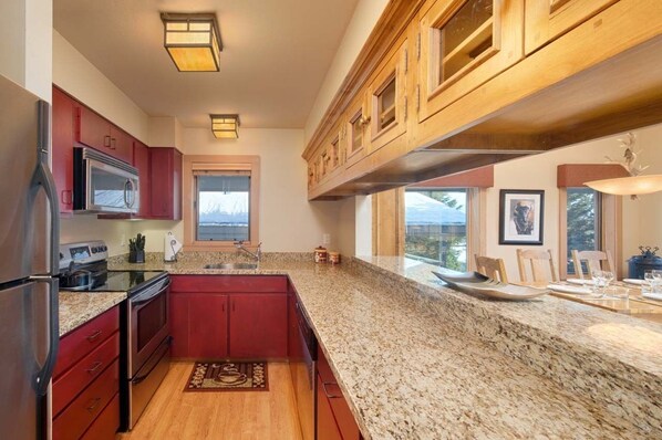 A kitchen with granite countertops, stainless steel appliances, and wooden cabinets. - JHRL - Rendezvous A6, third floor Teton Village condo, perfect for families or single vacationers (Teton Village)
