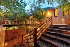 A staircase with wooden railings leading to a building with a thatched roof. - Luxe Beach Villa in 5-star Oceanfront Community (Huatulco)