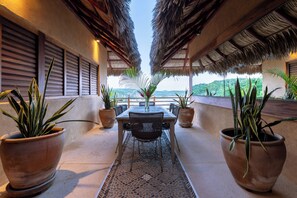 A terrace with a table and chairs, surrounded by potted plants, and overlooking a scenic landscape. - Luxe Beach Villa in 5-star Oceanfront Community (Huatulco)