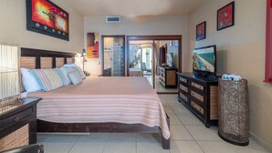 Una camera d'albergo con un letto, una cassettiera, una televisione e opere d'arte alle pareti.