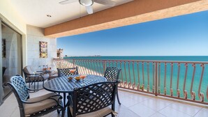 Un balcone con tavolo e sedie, vista sul mare e ringhiera.