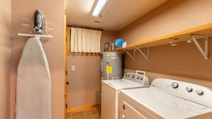 Un cuarto de lavandería con lavadora, secadora y calentador de agua.